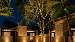 A modern outdoor pool area with stone walls and a tree. - Makham Villa River Kwai (Kanchanaburi)