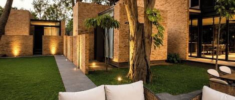 A modern outdoor patio with a sofa, a wooden table, and a potted plant.