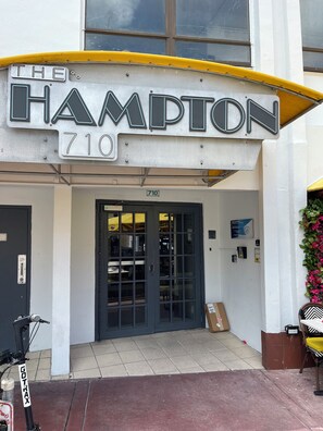 Ein Gebäude mit einem Schild, auf dem 'The Hampton 710' steht, und einer Tür mit einer Glasverkleidung.