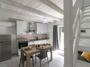 Een moderne keuken met witte kasten, een houten eettafel en een inbouwoven.