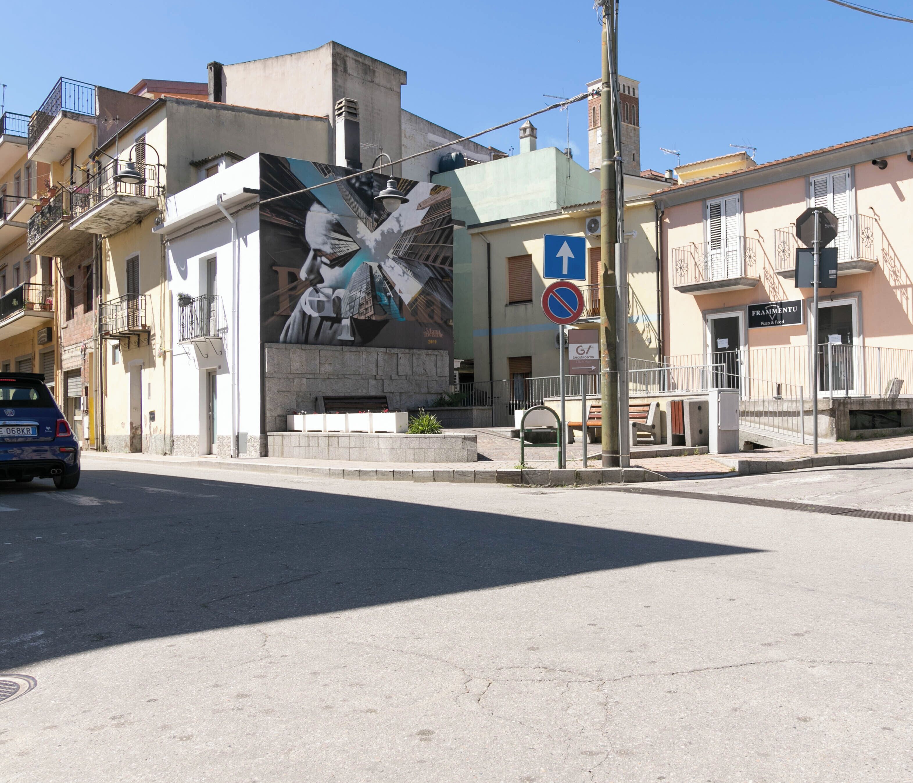 A street corner with a mural, a no parking sign, and a building with a sign that reads 'Frammenti.'