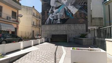 Una calle con un mural grande, una zona pavimentada y un banco.
