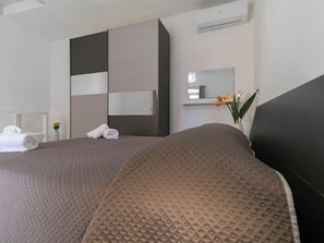Ein Hotelzimmer mit zwei Betten, einem großen Spiegel, einem Kleiderschrank und einem Blumentopf.