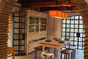 A rustic dining area with a wooden table, benches, and a cabinet with glass doors.