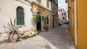 A narrow cobblestone street with a yellow building, a scooter, and a potted plant. - Dei Vecchi Casa by Corfuescapes  (Corfu)