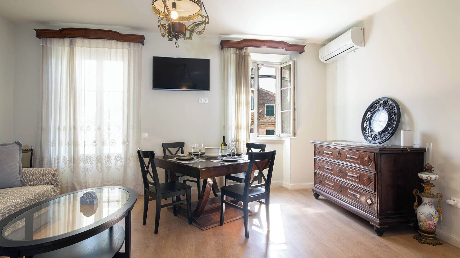 Un espace repas comprenant une table, des chaises, un téléviseur et une commode avec un miroir.