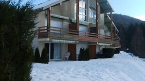Un edifici modern d'àmbit superior amb grans finestres, un balcó i un paisatge cobert de neu.