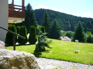 A view of a mountainous landscape with a building, a grassy area, and a rock. - Charming Ground-Floor Apartment in Chalet with Garden Terrace (Gérardmer)