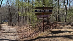 Un área boscosa con un indicador señalando direcciones a Wood River Access, Campfire, Fairy Pond y el estacionamiento.