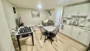 Un espacio habitable compacto con mesa de futbolín, mesa de comedor y kitchenette.