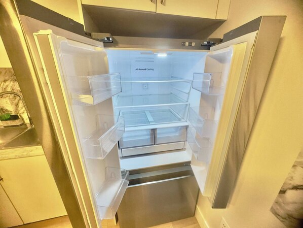 Refrigerador con enfriamiento total, múltiples cajones transparentes y acabado de acero inoxidable.