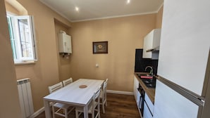 A compact kitchen with a dining table, white cabinets, a built-in oven, and a window with a view. - A stone's throw from the sea and the heart of the city (Livorno)
