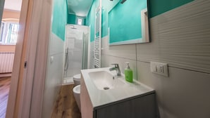 A bathroom with a white sink, a mirror, and a shower. - A stone's throw from the sea and the heart of the city (Livorno)