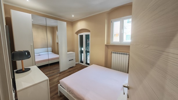 A bedroom with a bed, a wardrobe, a desk, and a radiator. - A stone's throw from the sea and the heart of the city (Livorno)
