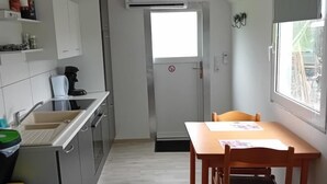Een kleine keuken met een eethoek, een raam en een deur met een rookvrij bordje.