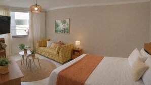 Hotellihuone, jossa on sänky, sohva, televisio, pieni pöytä, jossa on kasveja, ja taulu seinällä.