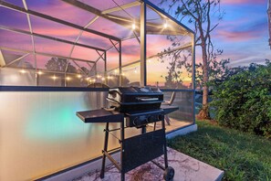 A covered outdoor area with a grill, a glass enclosure, and a view of the sky. - Stylish 3BR, Pool, Golf Views, Disney and Legoland (Haines City)