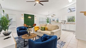 A modern living room with a ceiling fan, a sofa, a coffee table, and a green wall. - Stylish 3BR, Pool, Golf Views, Disney and Legoland (Haines City)