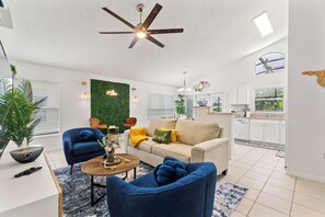 A modern living room with a ceiling fan, a sofa, a coffee table, and a green wall. - Stylish 3BR, Pool, Golf Views, Disney and Legoland (Haines City)