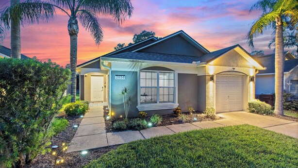 A residential house with a garage, a well-maintained lawn, and a clear sky. - Stylish 3BR, Pool, Golf Views, Disney and Legoland (Haines City)