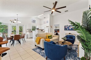 A spacious living area with a dining table, sofas, a ceiling fan, and a kitchen in the background. - Stylish 3BR, Pool, Golf Views, Disney and Legoland (Haines City)