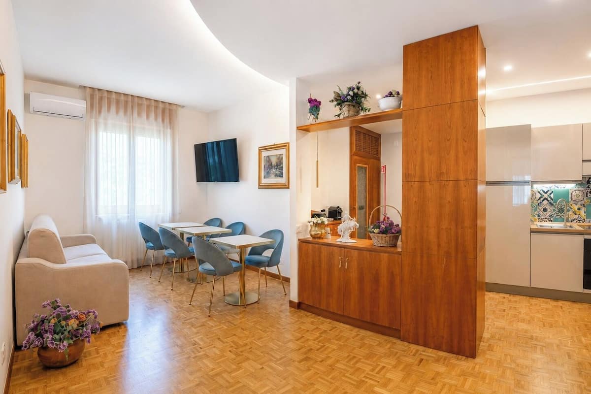 Ein modernes Wohnzimmer mit einer Couch, einer Essecke mit Stühlen, einer Küche mit Schränken und einem Holztrennwand.