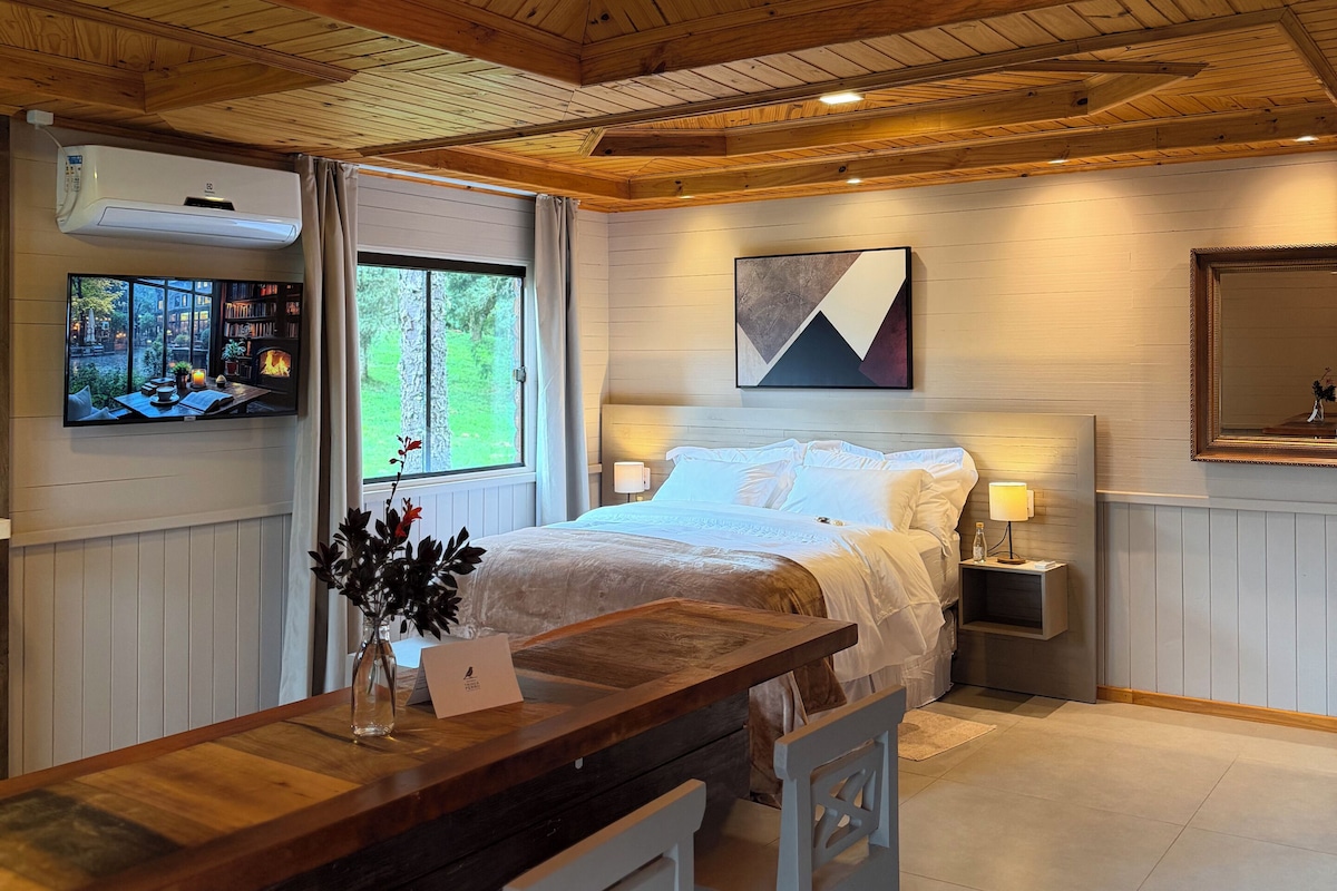Une chambre avec un plafond en bois, un lit, des tables de chevet, une télévision et une fenêtre.
