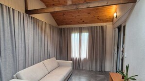 Una sala moderna con sofá, cortinas y un banco de madera.
