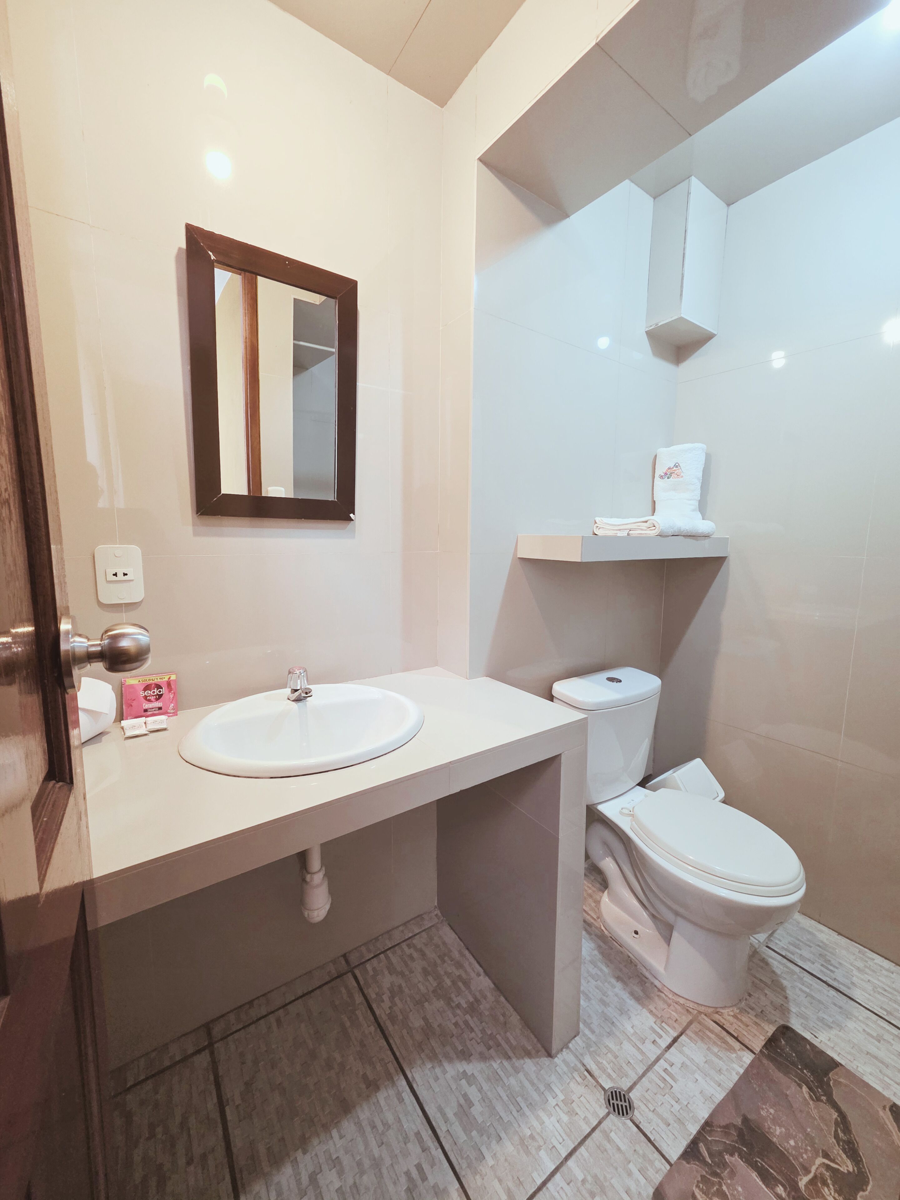 Une salle de bain avec un lavabo blanc, un miroir et des toilettes.