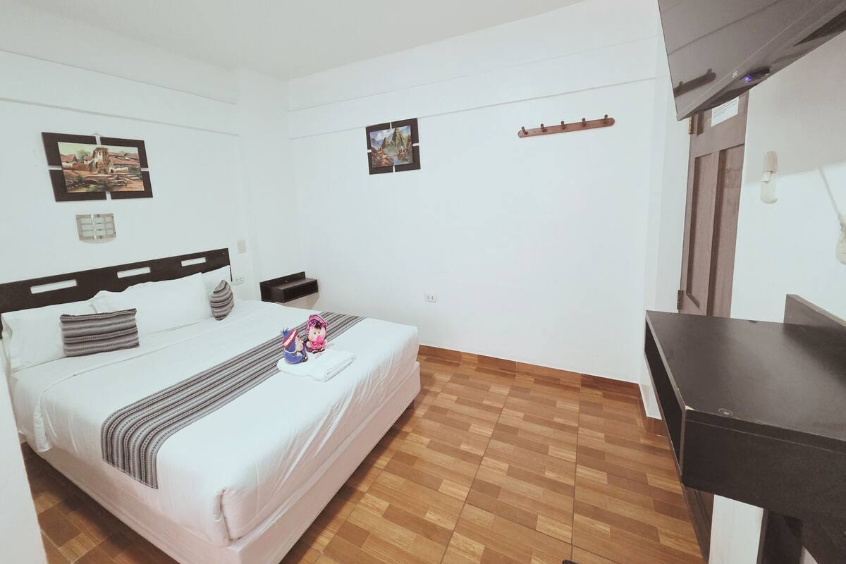 Ein Hotelzimmer mit einem Bett, einem Schreibtisch und zwei an der Wand befestigten Bildern.