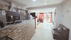 A kitchen with a countertop, a sink, and a stove. There is a sofa and a television in the living area. - Alegria's INN machupicchu (Aguas Calientes)