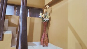 A staircase with a wooden handrail, a vase with flowers, and a framed picture on the wall. - Alegria's INN machupicchu (Aguas Calientes)