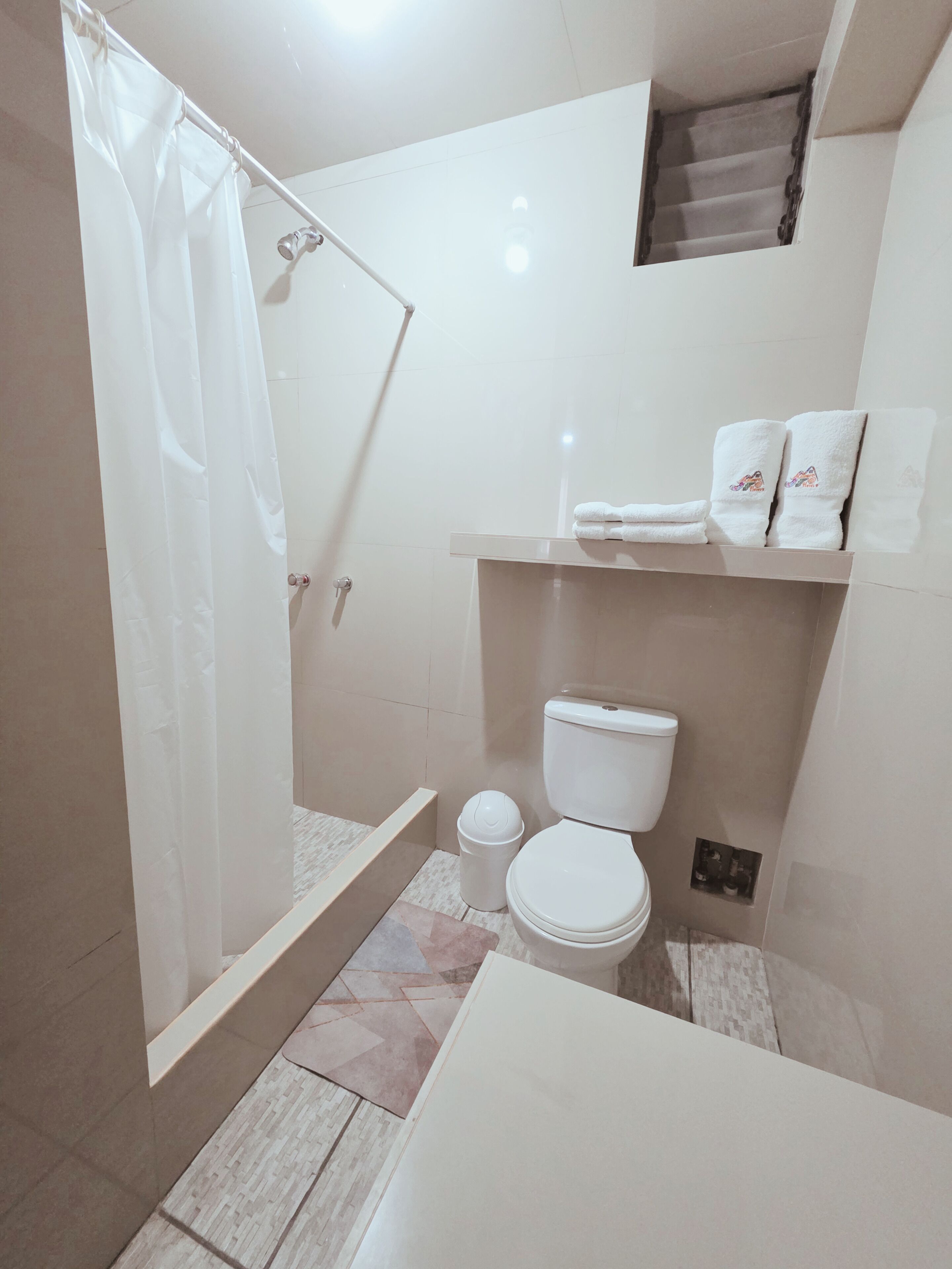 Un baño con ducha, inodoro y un estante con toallas.