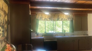 Una cocina con ventana, armarios de madera y una mesa con un jarrón de flores.