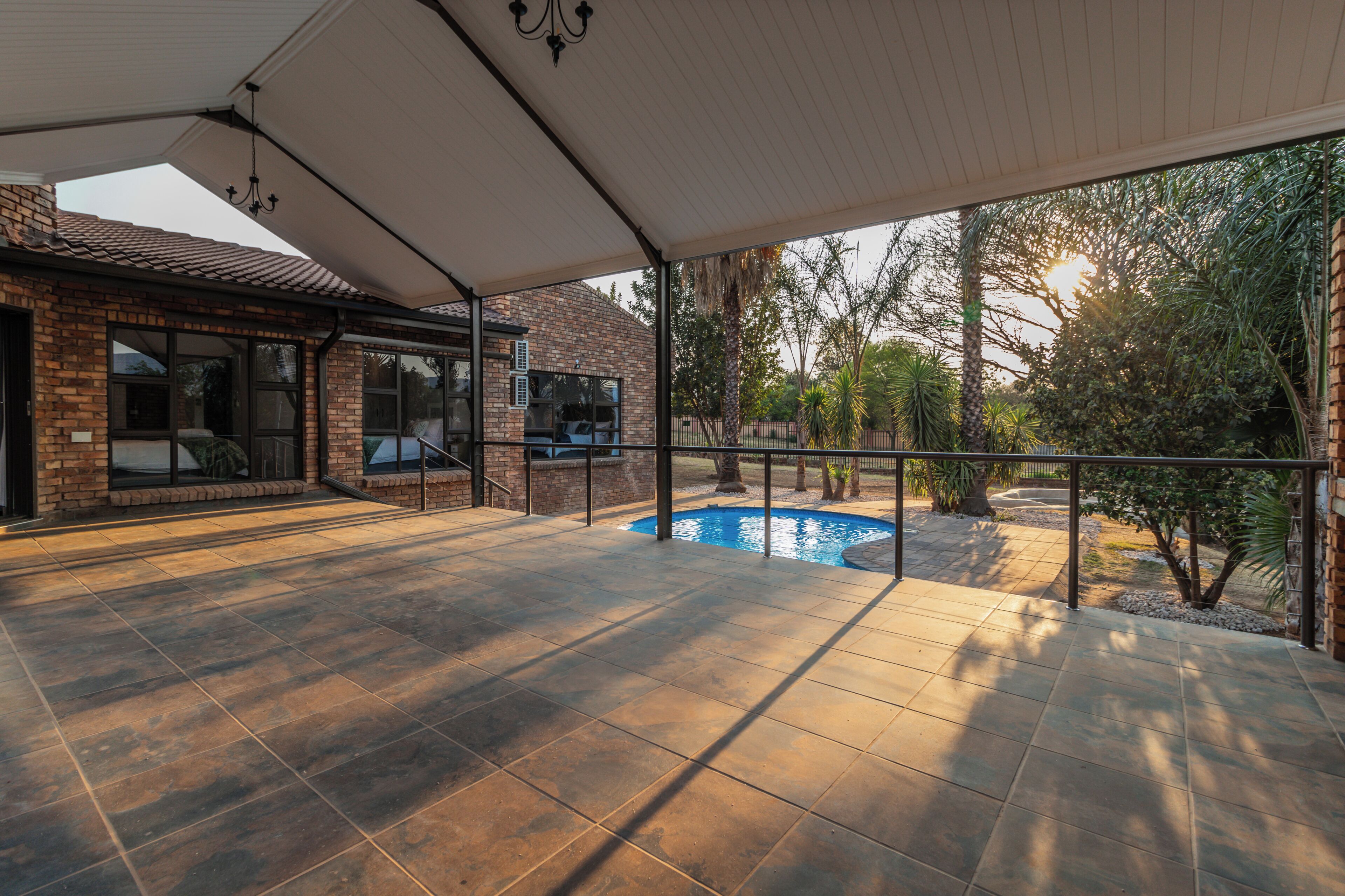 Un patio abrité avec une piscine, des murs en briques et une vue sur le paysage environnant.