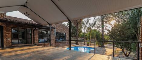 Un patio abrité avec une piscine, des murs en briques et une vue sur le paysage environnant.