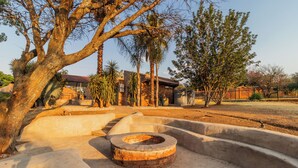 A circular outdoor seating area with a fire pit, surrounded by concrete steps and palm trees.