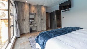 A bedroom with a bed, a TV, a wardrobe, and a bathroom.