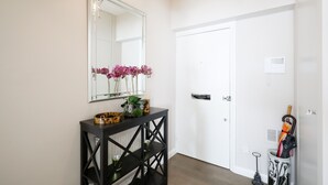 A hallway with a black console table, a mirror, and a door. - Elegant 2BR Belgravia Flat w/ Lift | Near Victoria (London)