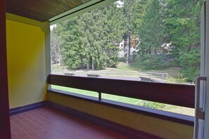Ein Zimmer mit Fensterblick auf eine Wiese und Bäume.