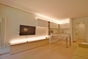 Eine moderne Küche mit Flachbildfernseher, einer Essecke mit Stühlen und einer Couch.