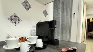 Una cocina moderna con una cafetera, tazas y platitos sobre la encimera.