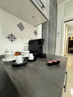A modern kitchen with a coffee maker, cups, and saucers on the counter. - Family apartment with garden in the center of Bari (Bari)