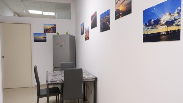 A dining area with a table and chairs, a refrigerator, and a door. - Family apartment with garden in the center of Bari (Bari)