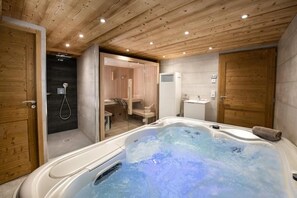 Ein Spa-Raum mit Whirlpool, Holzboden und Duschbereich.