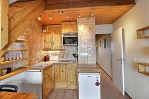 Eine kleine Küche mit Holzausstattung, einer Mikrowelle und einem Kühlschrank.