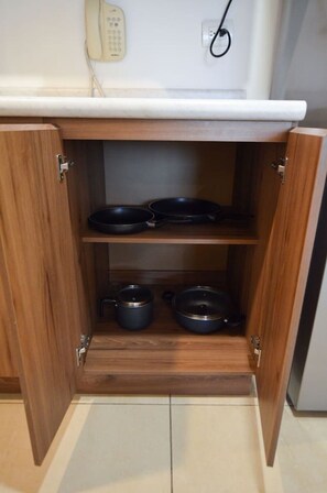 A kitchen cabinet with two black pots and a pan on the upper shelf, and two black pots on the lower shelf. - Stay in Obispado! Security 24/7 4 beds 2BR2br 6ppl (Monterrey)
