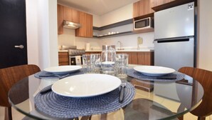 Een moderne keuken met een glazen eettafel, houten stoelen en een magnetron.