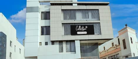 A modern building with a 'Collection' sign, large windows, and a visible entrance with steps.