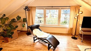 A sun lounger in a room with wooden flooring, a large window, and a radiator. - Rooftop Lounge Studio Apartment directly at the University Hospital Homburg (Homburg)